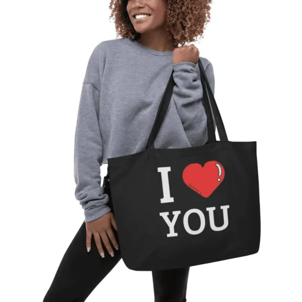 femme souriante portant un large organic tote bag noir à l'épaule imprimé I love you